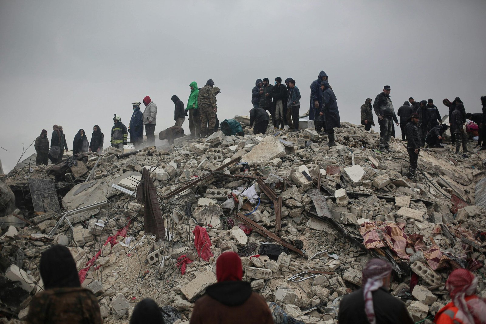 Survivors and rescuers search through rubble after a disaster in Idlib, Syria.