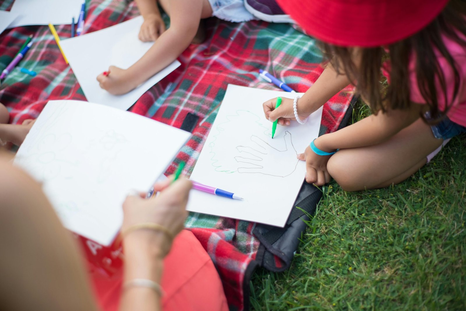 Kids engaging in creative activities on a picnic blanket outdoors during daytime in Portugal.